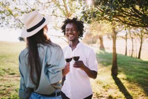a woman and man outside drinking wine and cheersing